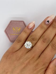 a woman's hand holding a ring with a diamond on it and a pin