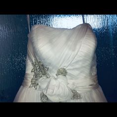 a white wedding dress hanging up against a blue wall with water droplets on the glass behind it