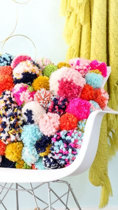 a white chair covered in multicolored pom - poms