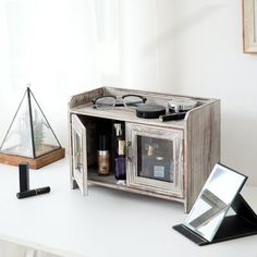 an old wooden cabinet with glasses and other items in it next to a candle holder