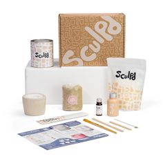 an assortment of crafting supplies sitting on top of a white table next to a box