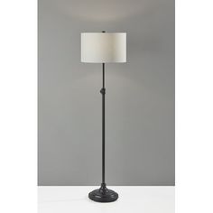 a floor lamp with a white shade on it's side and a black base