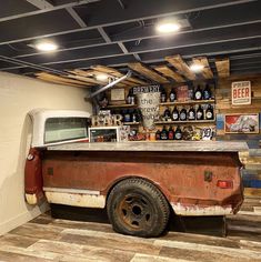 an old pickup truck is parked in a garage with beer bottles on the wall behind it