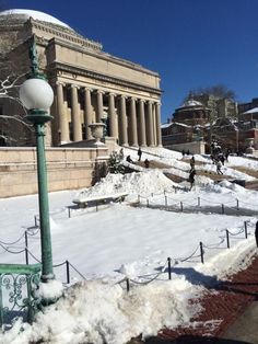 a street light covered in snow next to a building with columns and pillars on it