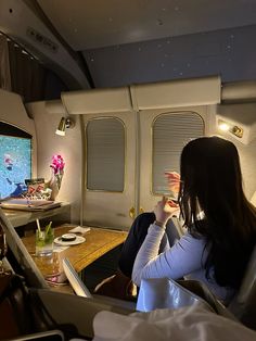 a woman sitting in an airplane watching tv