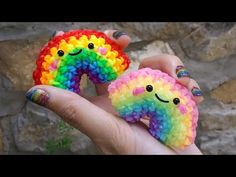 someone is holding two small rainbow rings in their hand, one has a smiley face on it