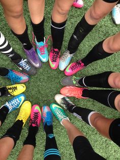 a group of people standing in a circle on top of green grass with colorful shoes