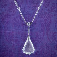 A fabulous Art Deco lavaliere necklace from the early 20th Century adorned with a large glass pendant hanging from the bottom. The glass has been expertly cut into a striking teardrop shape with glistening facets and a jagged edge.  The ornate links are crafted in silver metal and decorated with further glass pastes in various shapes and sizes. It's a distinctive design and would be perfect for a glamorous occasion. WEIGHT: 22.7 grams MEASURES: Length 16 inches x Width 3 - 10mm - Pendant Height Large Glass Pendant, Glamorous Jewelry, Jagged Edge, Antique Necklaces, Gold Heart Necklace, Antique Necklace, Art Deco Era, Metal Style, Glass Pendant