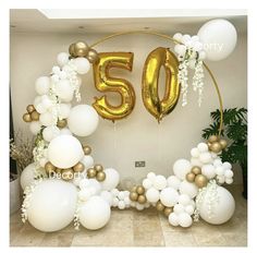 white and gold balloons with the number 50 displayed in front of a large balloon arch