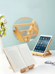 an open book sitting on top of a table next to a white vase filled with flowers