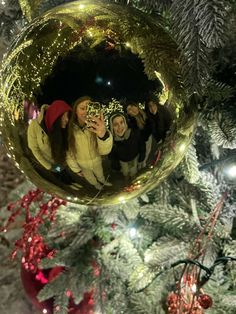 a group of people taking a selfie in a christmas ornament on a tree