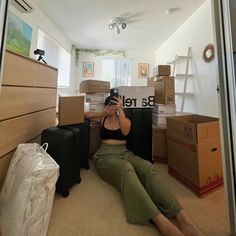 a woman sitting on the floor taking a selfie with her cell phone in front of boxes