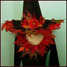 a woman wearing a black hat with red leaves on it