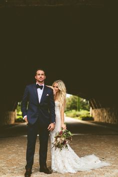 a man and woman in formal wear standing next to each other on a cobblestone walkway