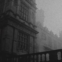 a black and white photo of an old building on a foggy day