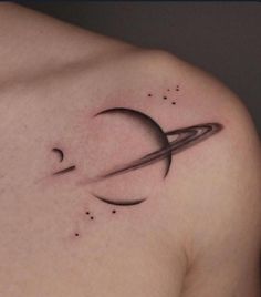 a small saturn tattoo on the back of a man's left shoulder and chest