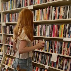 a woman standing in front of a book shelf filled with books