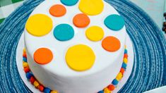 a white cake with multicolored polka dots on it sitting on a blue plate