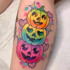 a woman's leg with colorful tattoos on her legs and pumpkins in the shape of faces