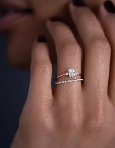 a woman's hand with a diamond ring on top of her finger and an engagement band