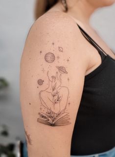 a woman with a tattoo on her arm holding an open book and looking at the sky