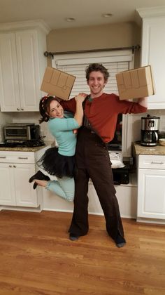 a man and woman posing for a photo with boxes on their heads in the kitchen