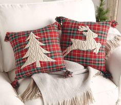 two red plaid christmas pillows on a white chair with fringe trimmings and trees