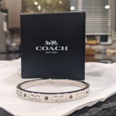 Item: Hinged Bangle Bracelet / Coach Pillow Gift Box Brand: Coach / Bangle Condition: New In Box Color: Silver Size: Diameter: 2 1/4" (L) X 2" (W) Details: Plated Brass And Glass Hinged Closure I Hope You Love It Too... Classic Coach Bangle Jewelry, Coach Classic Bangle Jewelry, Coach Bracelets As Gift, Coach Formal Bracelet Jewelry, Designer Round Cuff Bracelet As Gift, Coach Classic Bangle, Modern Coach Jewelry For Formal Occasions, Coach Formal Bracelet, Designer Bangle Jewelry As Gift