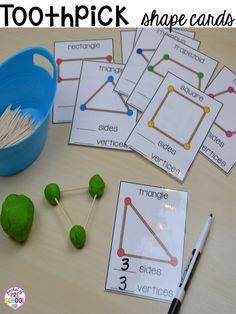 several different shapes and sizes of sticks on a table next to a blue container with strawberries