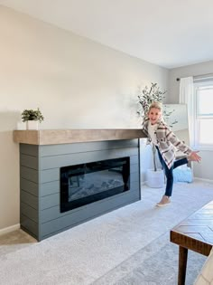 a girl is jumping in the air near a fireplace