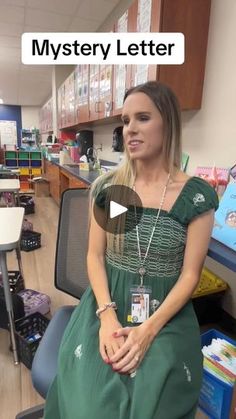 a woman in a green dress is sitting on a chair and talking to the camera