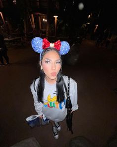 a woman with long hair wearing minnie mouse ears on top of her head at night