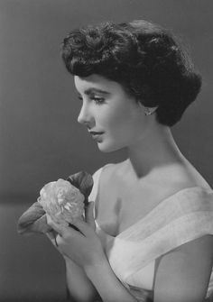 an old black and white photo of a woman holding a flower