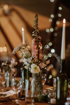 the table is set with candles and flowers in vases, plates and napkins