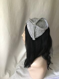 Absolutely beautiful! This is a silver vintage styled pearl beaded with rhinestone half hat fascinator perfect for weddings, Mother of the Bride hat, Bridal fascinator hat, Church hats, women convention hats, tea party, special occasion headpiece. E A S Y T O W E A R Forms to the contour of your head. Light weight One size fits all Silver pearl with rhinestone trim covered on a lightweight buckram base. S H I P P I N G : Expedited shipping upgrades are available at check out. We use Our local po Silver Evening Hat Headpiece, Silver Tall Crown Headpiece For Party, Silver Structured Crown Headpieces For Party, Party Headpiece With Rhinestones And Structured Crown, Silver Headpiece With Structured Crown For Party, Party Headpieces With Rhinestones And Structured Crown, Wedding Headpiece With Rhinestones And Round Crown, Elegant Mini Hats With Rhinestones For Weddings, Evening Headband With Rhinestones