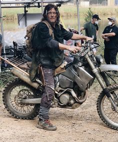 a man with dreadlocks on his head is sitting on a motorcycle in the mud