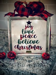 a glass block with the words joy love peace believe christmas on it