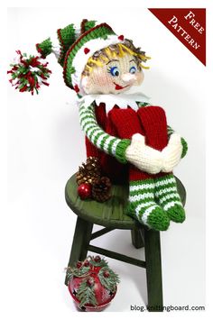 a knitted doll sitting on top of a wooden chair next to a christmas ornament