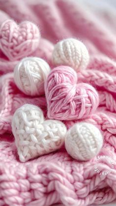 crocheted hearts on a pink blanket with white balls in the middle and one heart at the end