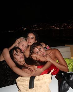 four women are hugging each other while sitting on a couch in the dark at night