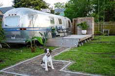 a dog is sitting in front of a camper and some steps leading up to it