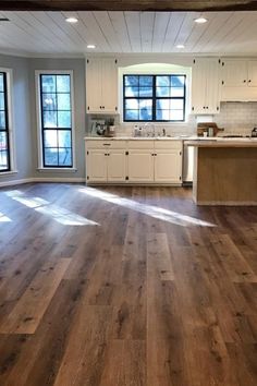 an empty kitchen with wood floors and white cabinets