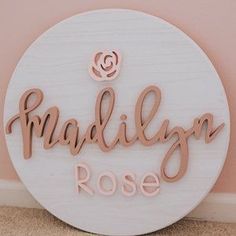 a wooden sign that says madison rose on the side of a wall with a pink background