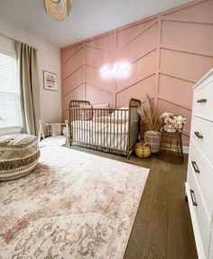 a baby's room with pink walls and white furniture, including a crib