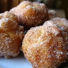 three sugared donuts on a plate with a green and yellow table cloth behind them