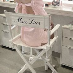 a woman sitting in a director's chair with the word miss dior on it