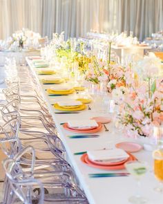 the long table is set with colorful plates and place settings