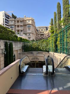 an escalator in the middle of a city with trees and buildings behind it