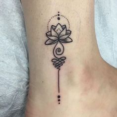 a woman's foot with a lotus tattoo on the side of her body and an arrow