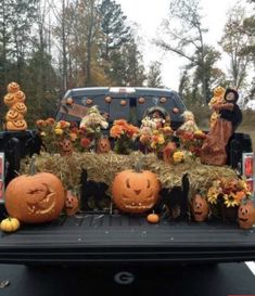 the back of a truck with pumpkins and hay on it's flat bed